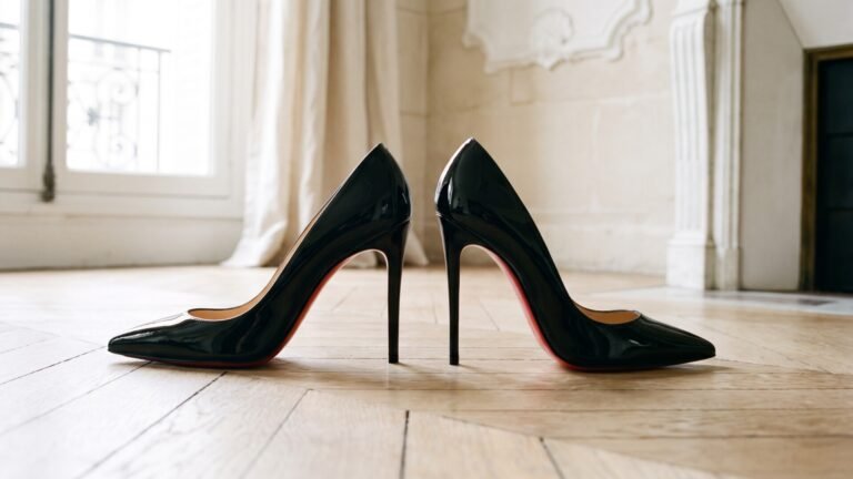 Side-by-side profile of black patent Christian Louboutin Kate and So Kate pumps showing heel arches and red soles