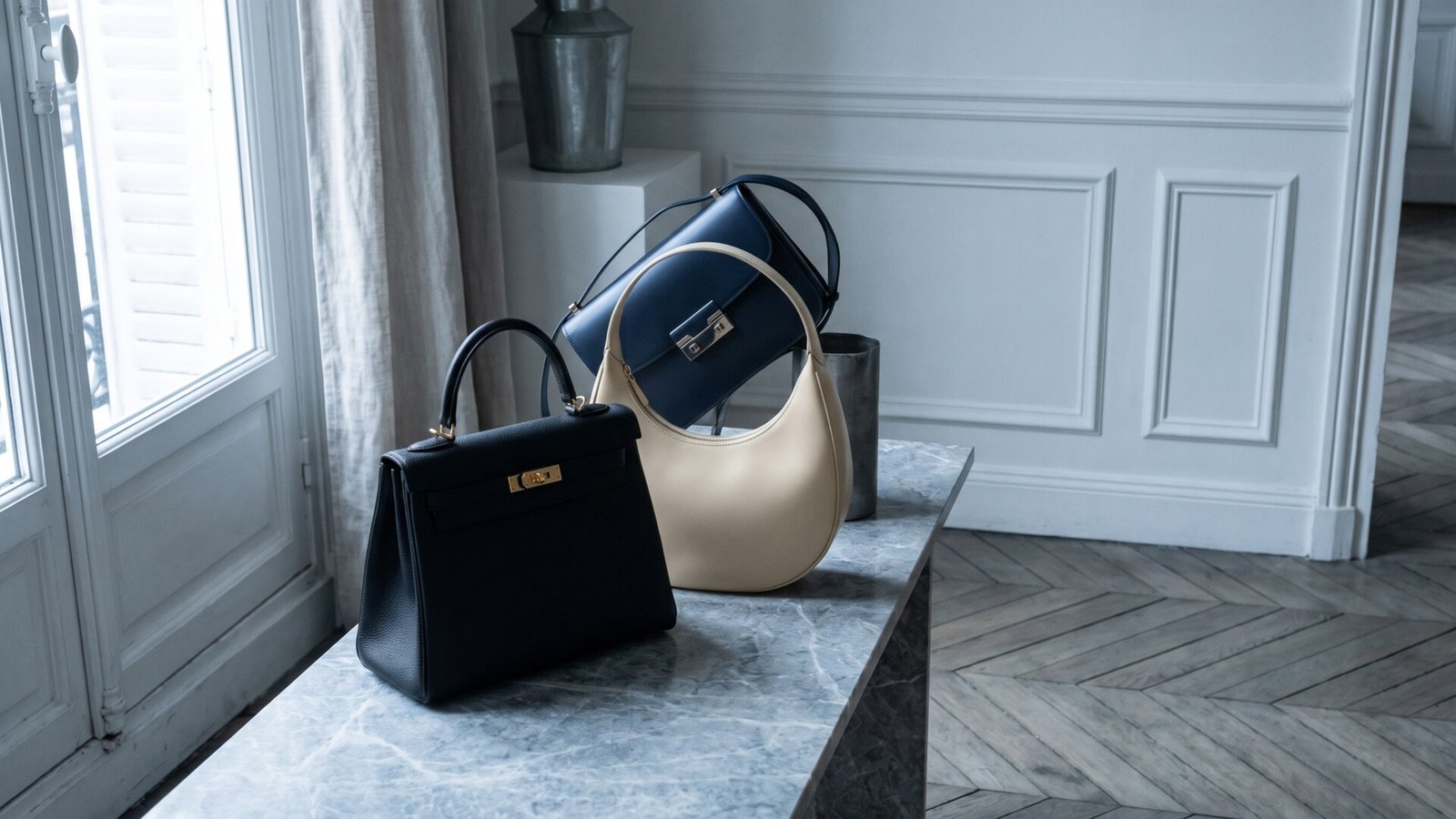 Curated French leather handbags on a marble console in an elegant Parisian apartment with parquet floors