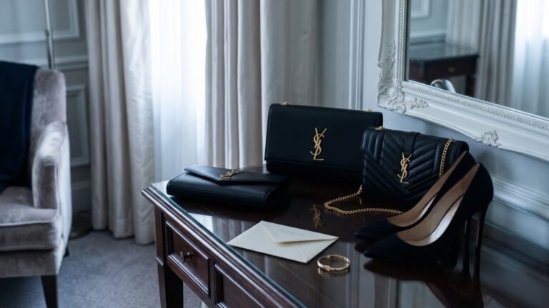 Black Saint Laurent evening bags displayed on a wooden dressing table with formal heels and accessories