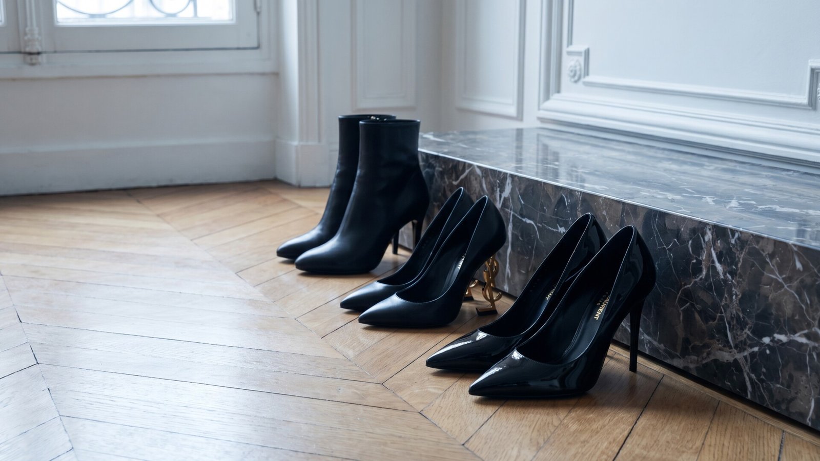 Saint Laurent patent pumps, Opyum heels with gold logo, and black leather ankle boots on parquet flooring