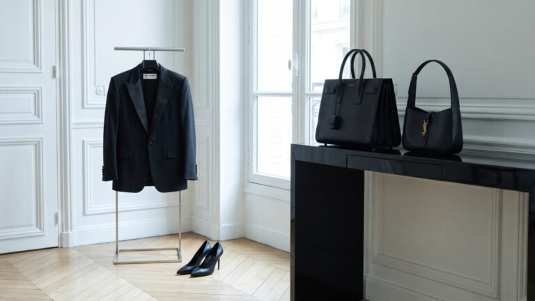 Black Saint Laurent tuxedo jacket on a rack beside matching pumps and contemporary leather handbags